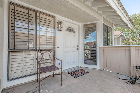 Front view of a house entrance with a white door and windows with shutters.