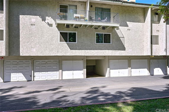 Front view of a multi-story building with garages on the ground level.