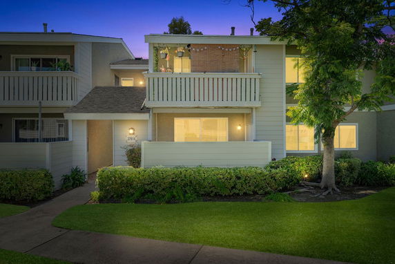 Front view of a two-story house with balconies and lit windows.