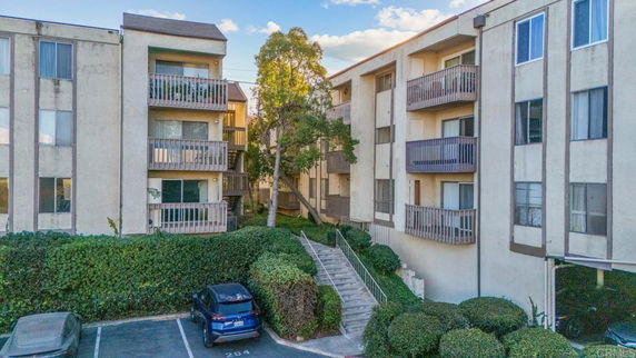 Front view of a multi-story apartment building with balconies and a staircase entrance.