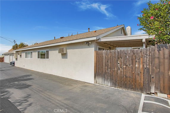 Side view of a single-story house with a wooden fence and an air conditioning unit.