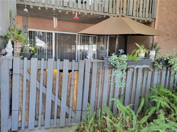Front view of a building with a fenced patio area and potted plants.