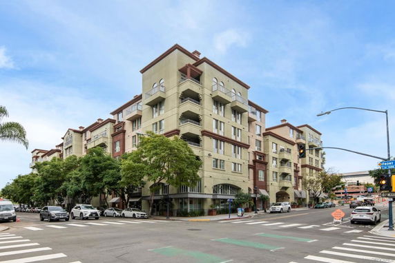 Front view of a multi-story residential building at a street intersection.