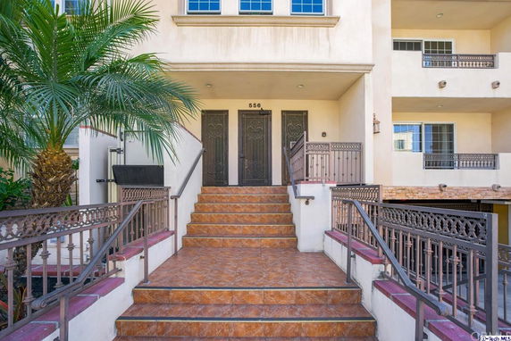 Front view of a building entrance with stairs and decorative iron railings.