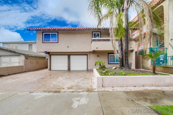 Front view of a two-story house with a double garage and palm trees.