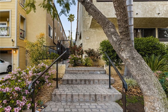 Front view of a multi-story building with walkway and staircase leading to entrance.