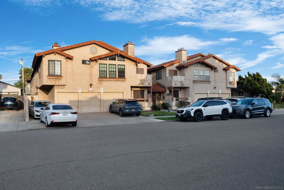 Front view of two-story houses with garages and multiple parked cars.