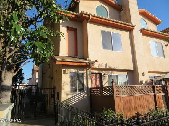 Front view of a multi-story residential building with a gated entrance.