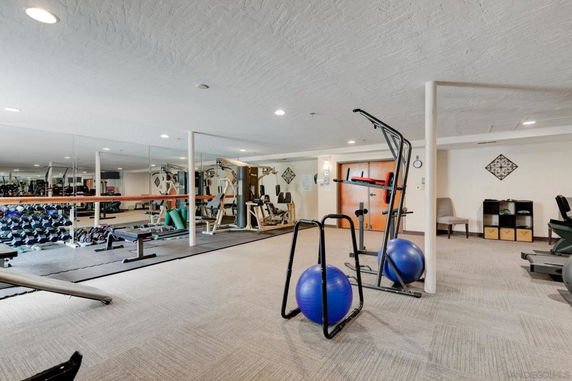Interior view of a gym area with various fitness equipment and mirrored walls.