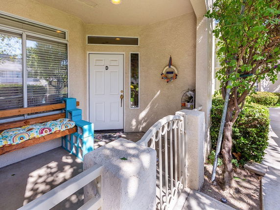 Front view of an entrance with a white door and small patio area.