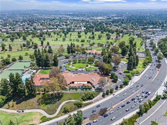 Aerial view of a large complex surrounded by roads and greenery with a cityscape in the background.