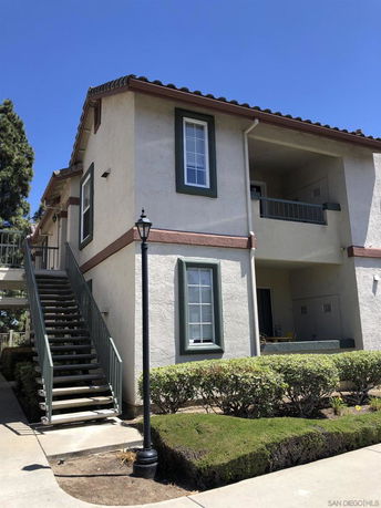 Front view of a two-story house with an outdoor staircase and green trim.