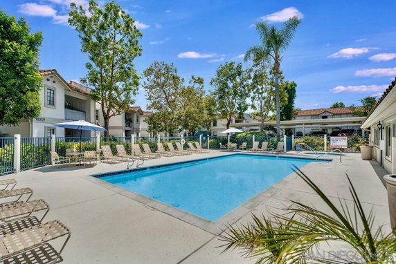 Outdoor swimming pool with surrounding lounge chairs and umbrellas.