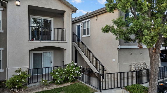 Front view of a two-story residential building with balconies and an external staircase.