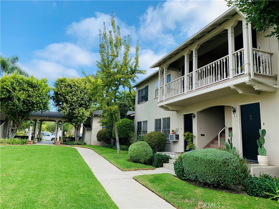 Front view of a two-story residential building with balcony and pathway.