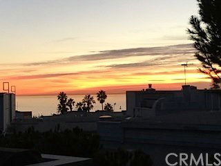 Panoramic view of rooftops with ocean and sunset in the background