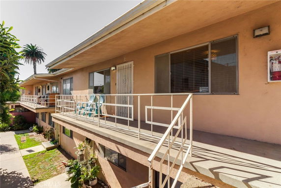 Front view of a two-story residential building with balconies and outdoor seating.