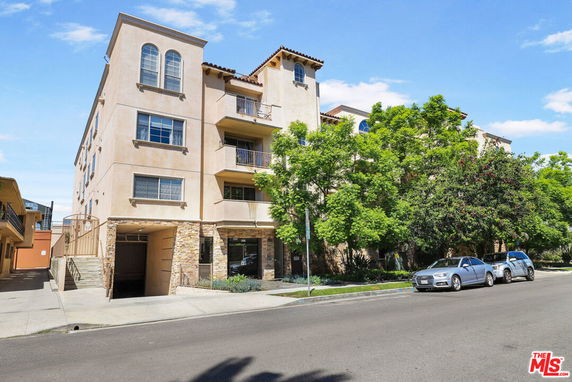 Front view of a multi-story residential building with balconies and trees.