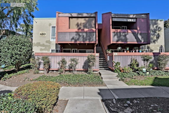 Front view of a two-story residential building with balconies and a central staircase.