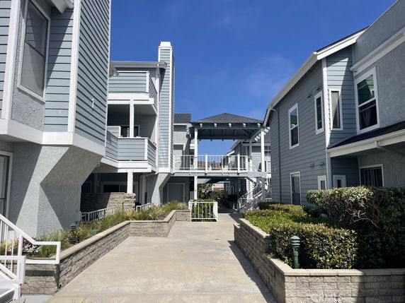 Front view of a multi-story building with balconies and a walkway.