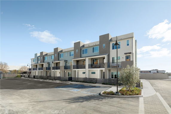 Front view of a multi-story residential building with balconies and flat roofs.