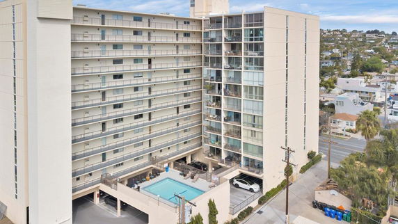 Elevated view of a multi-story building with a swimming pool at the base.