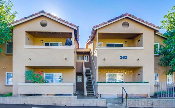 Front view of a two-story apartment building with balconies and an exterior staircase.