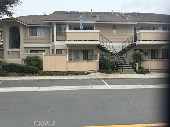 Front view of a two-story residential building with balconies and an external staircase.
