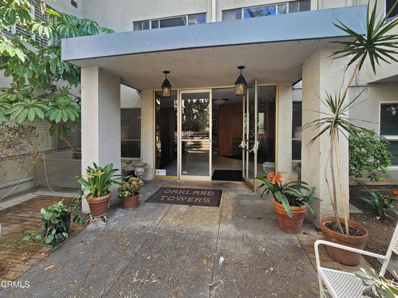 Front entrance of a building with a covered doorway and potted plants.