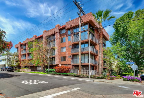 Front view of a multi-story brick apartment building with balconies.