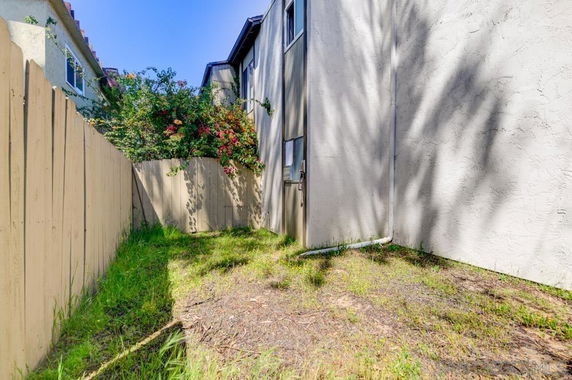 Side view of a building with a fenced area and plants.