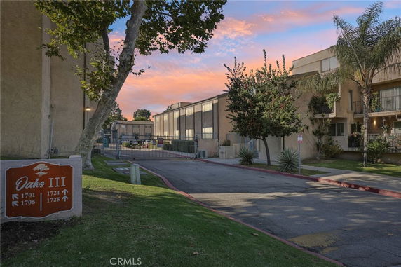Front view of a multi-story apartment complex with gated entrance and signage, 'Oaks III.'