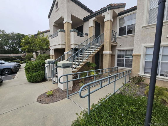 Front view of a two-story residential building with stairs and a ramp.