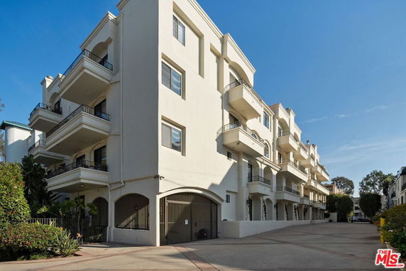 Front view of a multi-story building with balconies and gated entrance.
