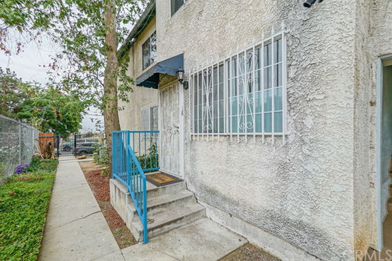 Side view of a two-story building with barred windows and a small entrance porch.