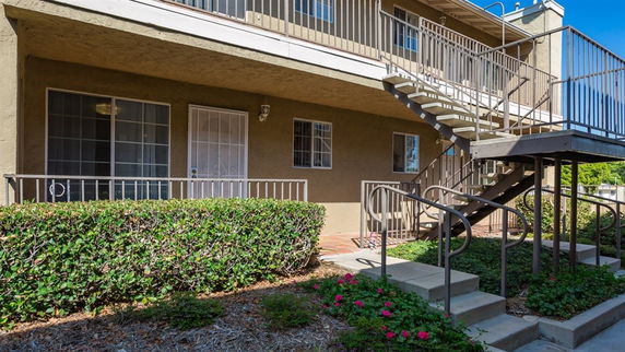 Front view of a two-story building with a staircase and small patio area.