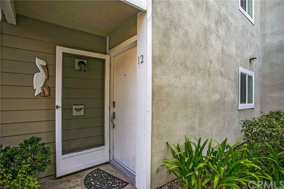 Front view of a house entrance with a storm door and wall decoration.