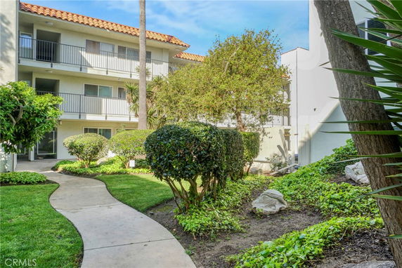 View of multi-story residential building with balconies, surrounded by landscaped gardens.