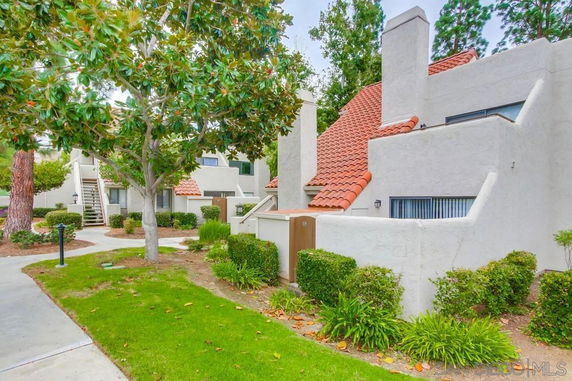 Front view of a residential building with red-tiled roofs and white exterior walls.