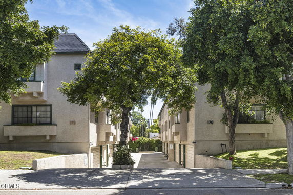Front view of a residential building with trees and a driveway.