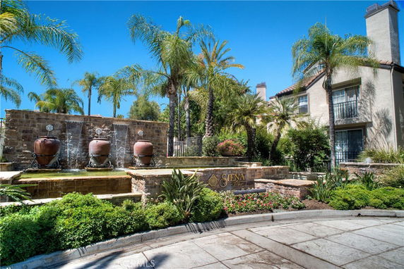 Front view of a residential complex with palm trees and a water feature.
