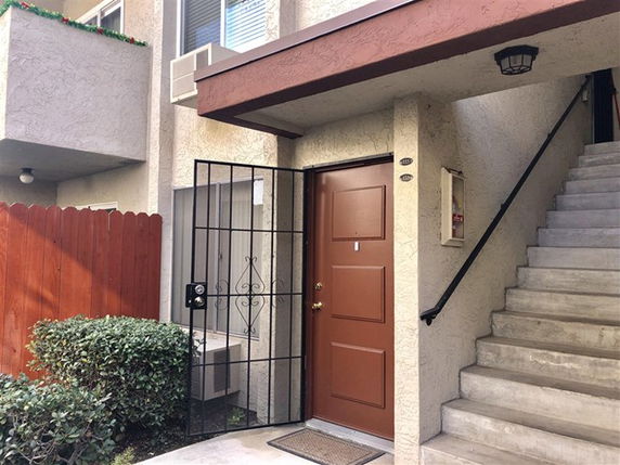 Front view of an apartment entrance with a stairway leading to an upper floor.