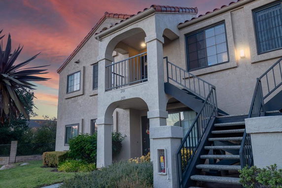 Front view of a two-story house with external staircases and arched entryway.