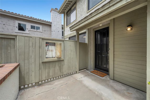 Front view of a house entrance with a black door and surrounding wooden fence.
