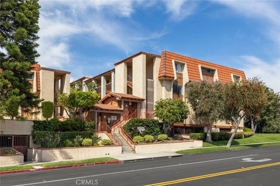 Front view of a multi-story residential building with a brick facade and sloped roof.