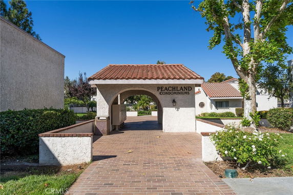 Front view of Peachland Condominiums with an archway and red-tiled roof.