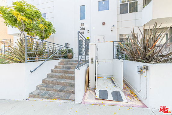 Front view of a modern building entrance with stairs and a wheelchair lift.