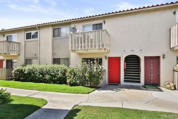 Front view of a two-story apartment building with balconies and red doors.