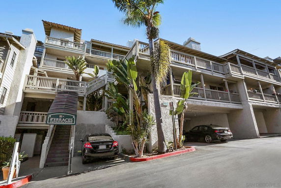 Front view of a multi-story residential building with balconies and covered parking.