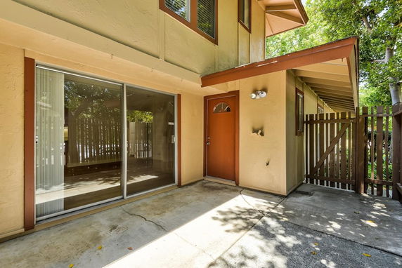 Front view of a house with a sliding glass door and a wooden front door.